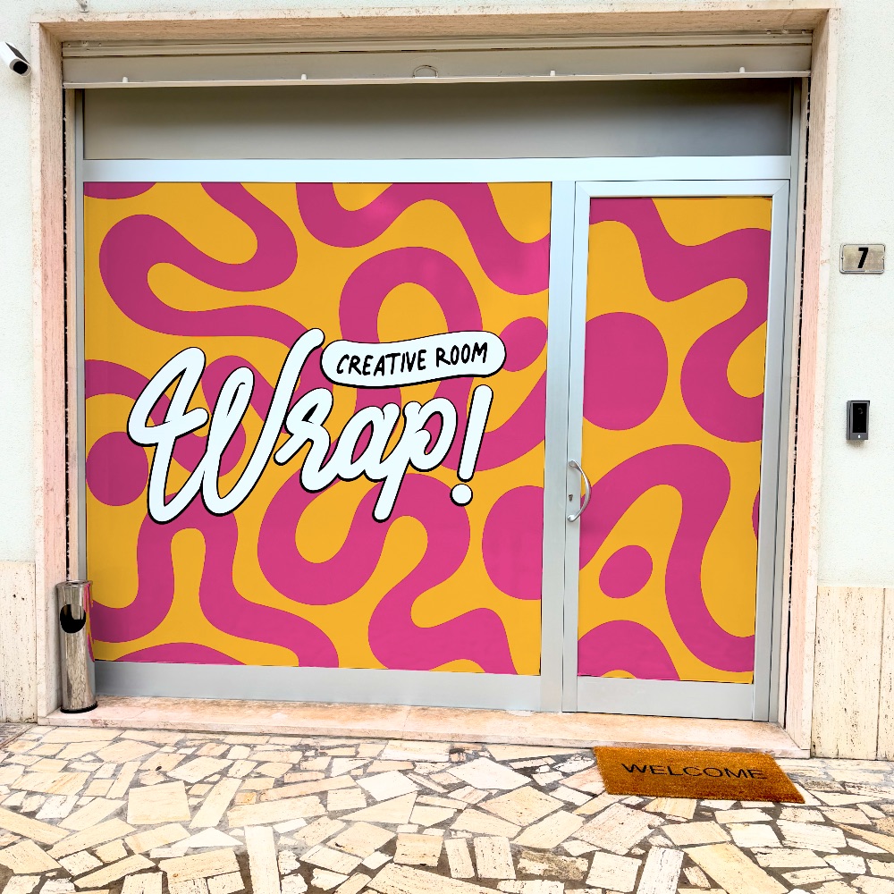 La vetrina di Wrap in Via Mazzini 7: onde fucsia su fondo giallo e il logo Wrap bianco